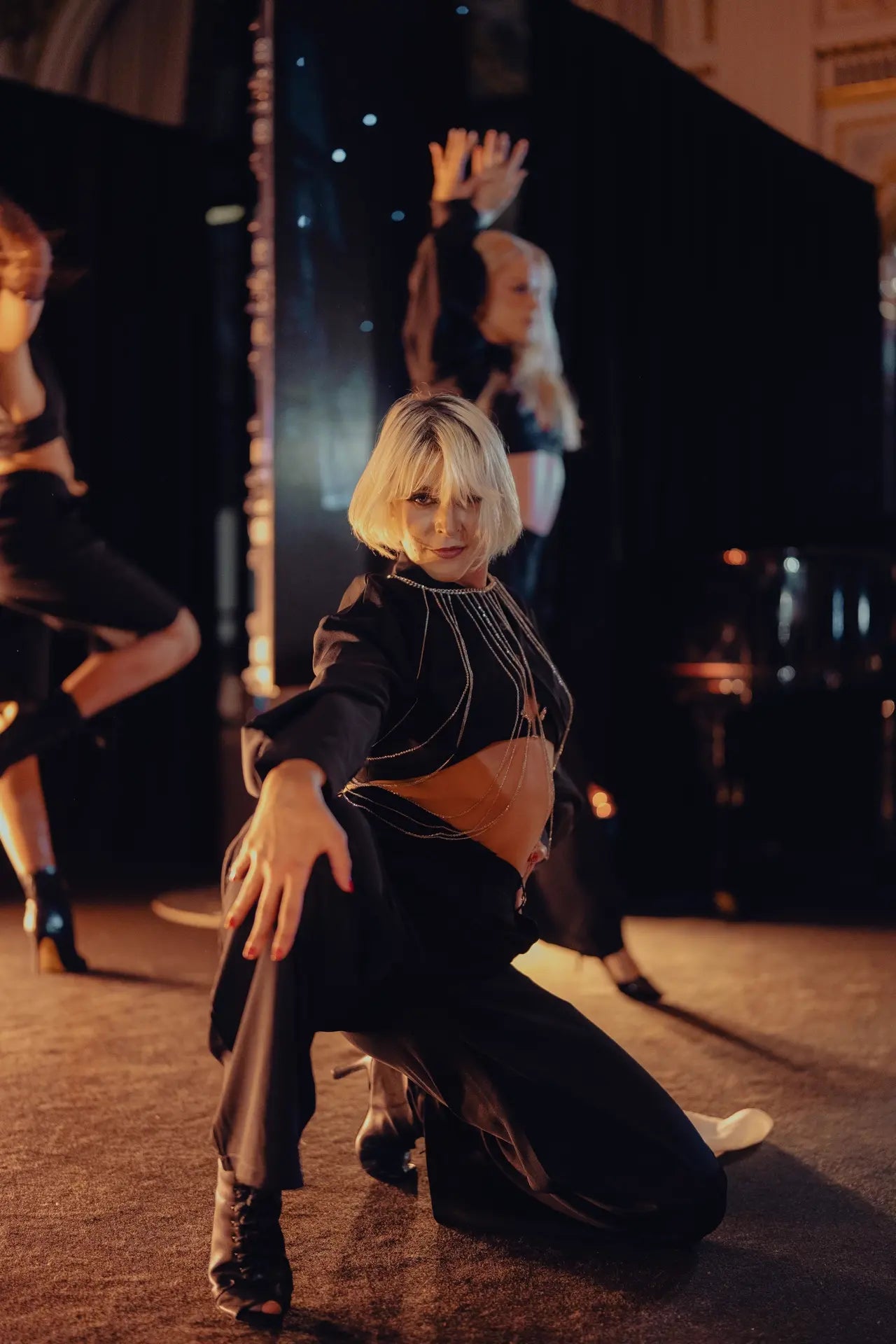 Danseuse en performance sur scène, regarde vers l'objectif, main sur son genou, attitude.