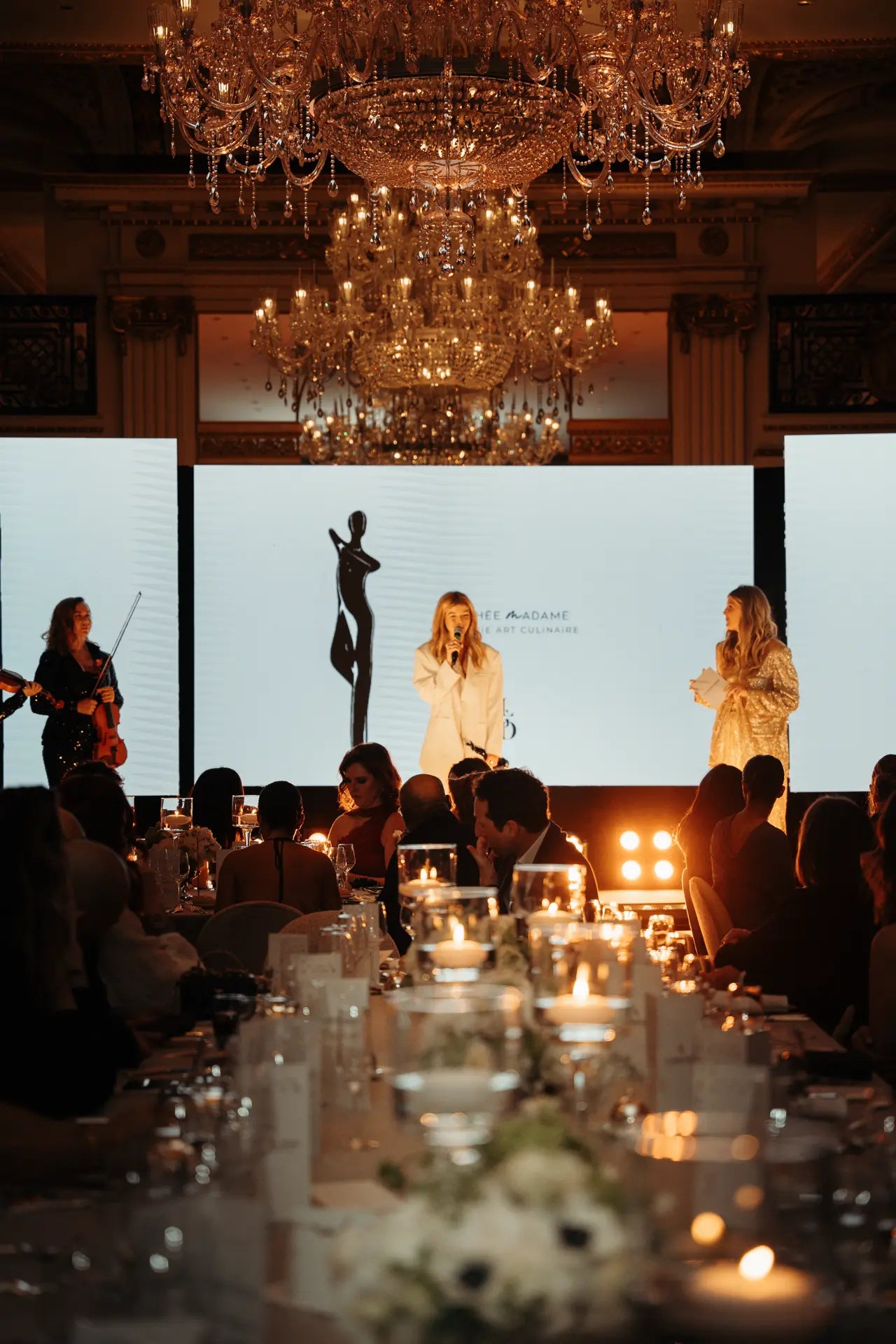 Emma Bertrand remercie Le Grand Dîner pour son prix. Vue sur une table au premier plan et la scène en fond