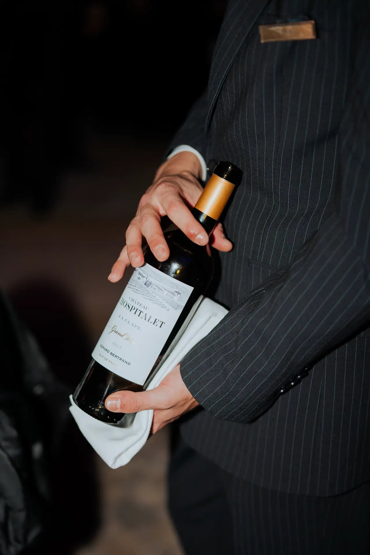Un serveur tient une bouteille de vin de notre partenaire Gérard Bertrand