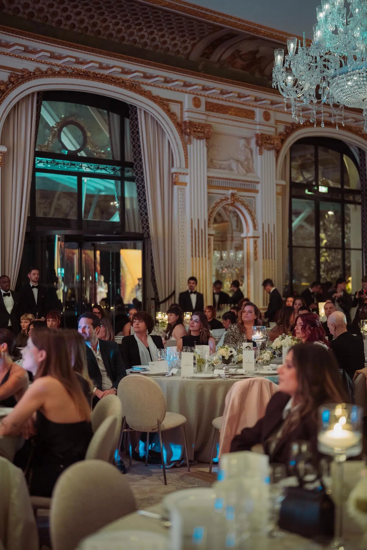 Vue de la salle pendant la cérémonie des Trophées Madame, les gens sont concentrés sur le discours. Vue large avec lustres et dorures